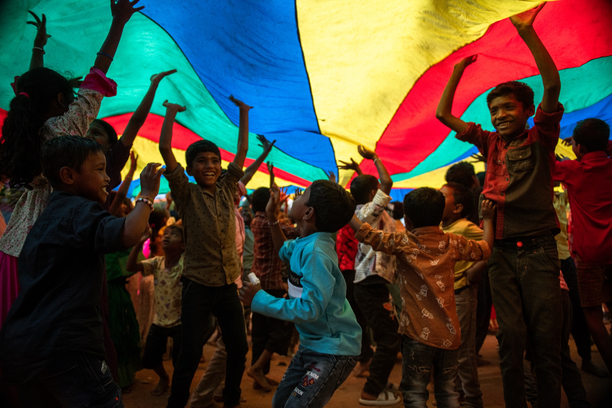 Children holding a colourful parachute together