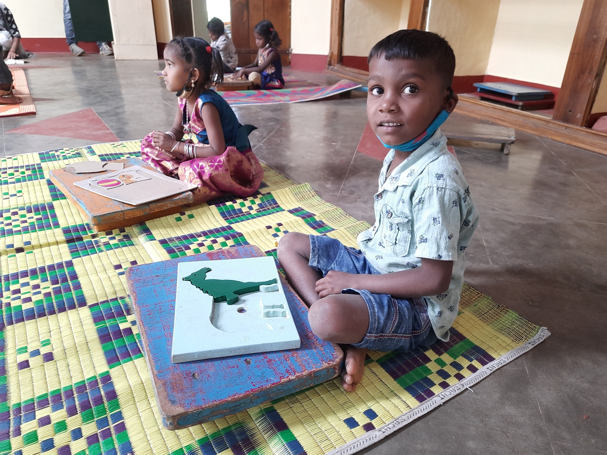 Boy seated on a mat with a map jigsaw puzzle in a learning-centre classroom