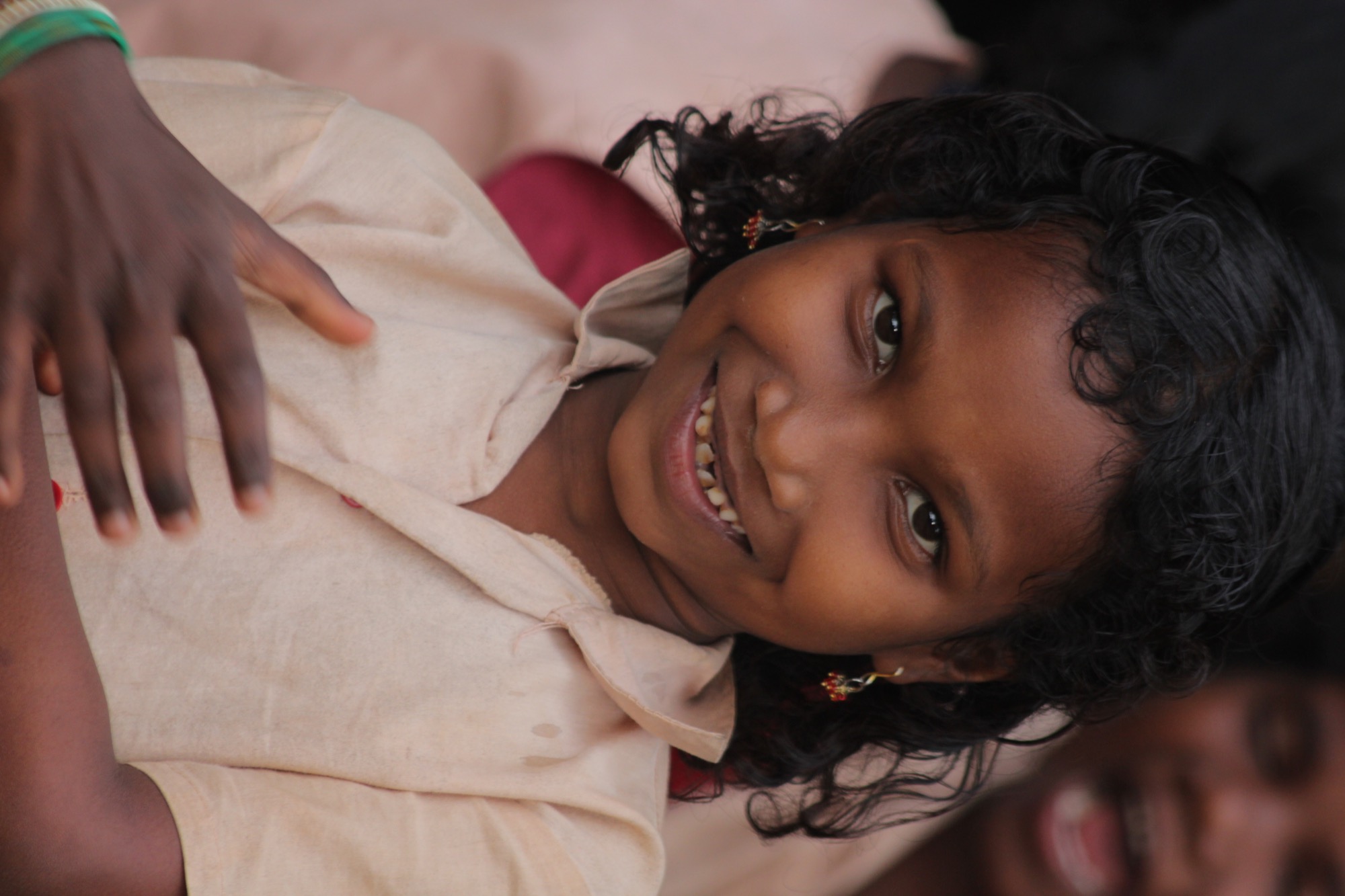 Close-up portrait of a smiling Adivasi girl in a cream school shirt