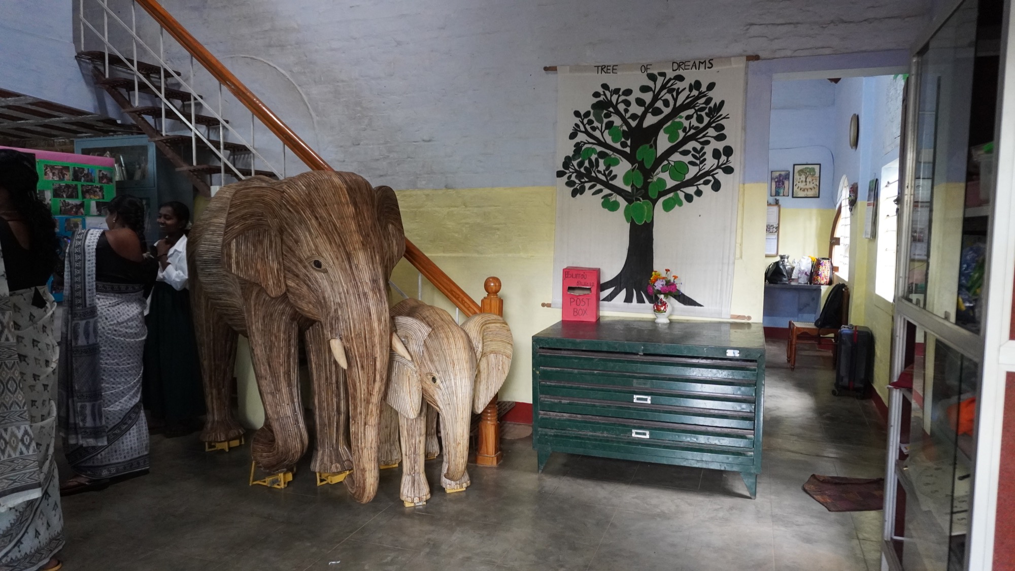 Hand-carved wooden elephant sculptures and a painted Tree of Dreams mural inside the campus building