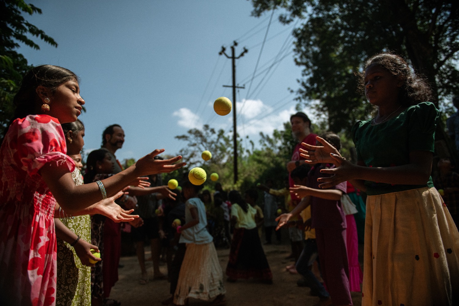 Children tossing and catching balls in pairs during an outdoor camp game